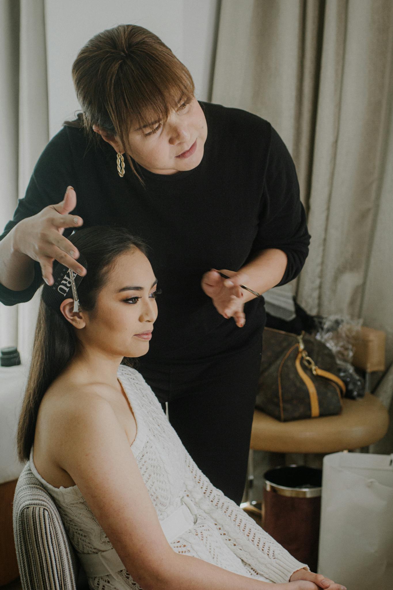Makeup artist applies finishing touches to client for a special occasion indoors.
