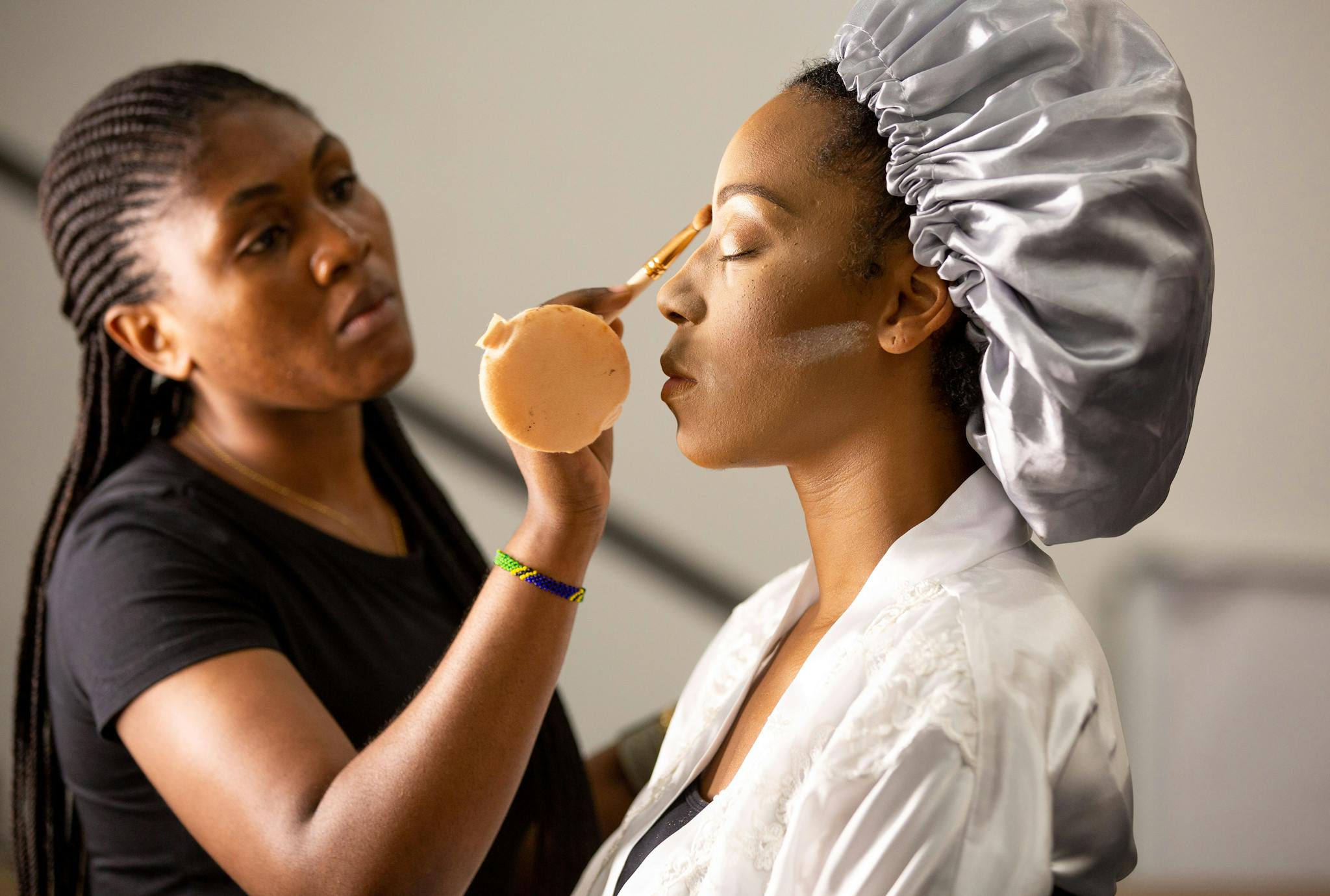 Makeup artist applying cosmetics to a client inside a salon.