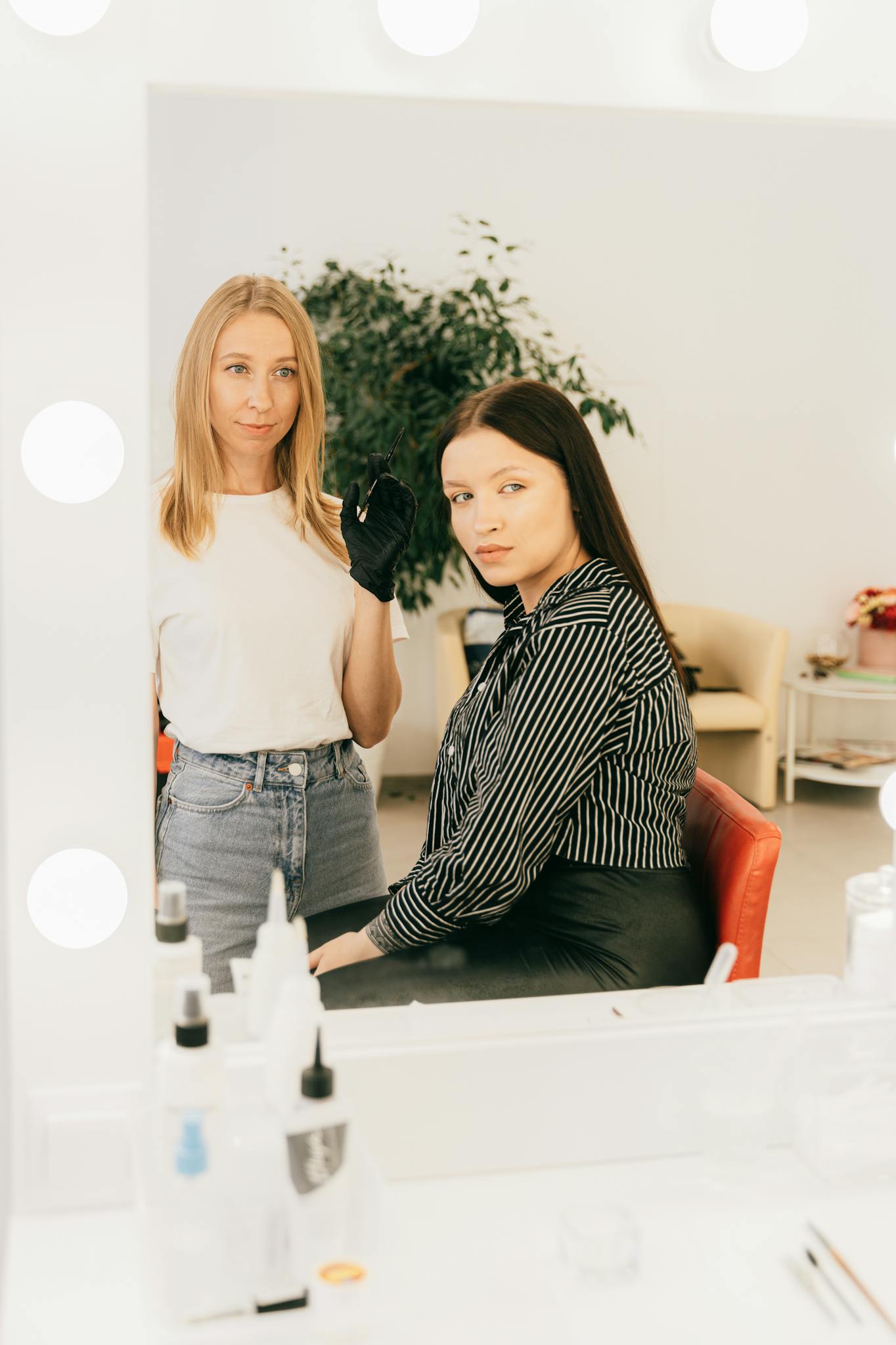 Makeup artist applying cosmetics to client in a modern salon with vanity mirror.