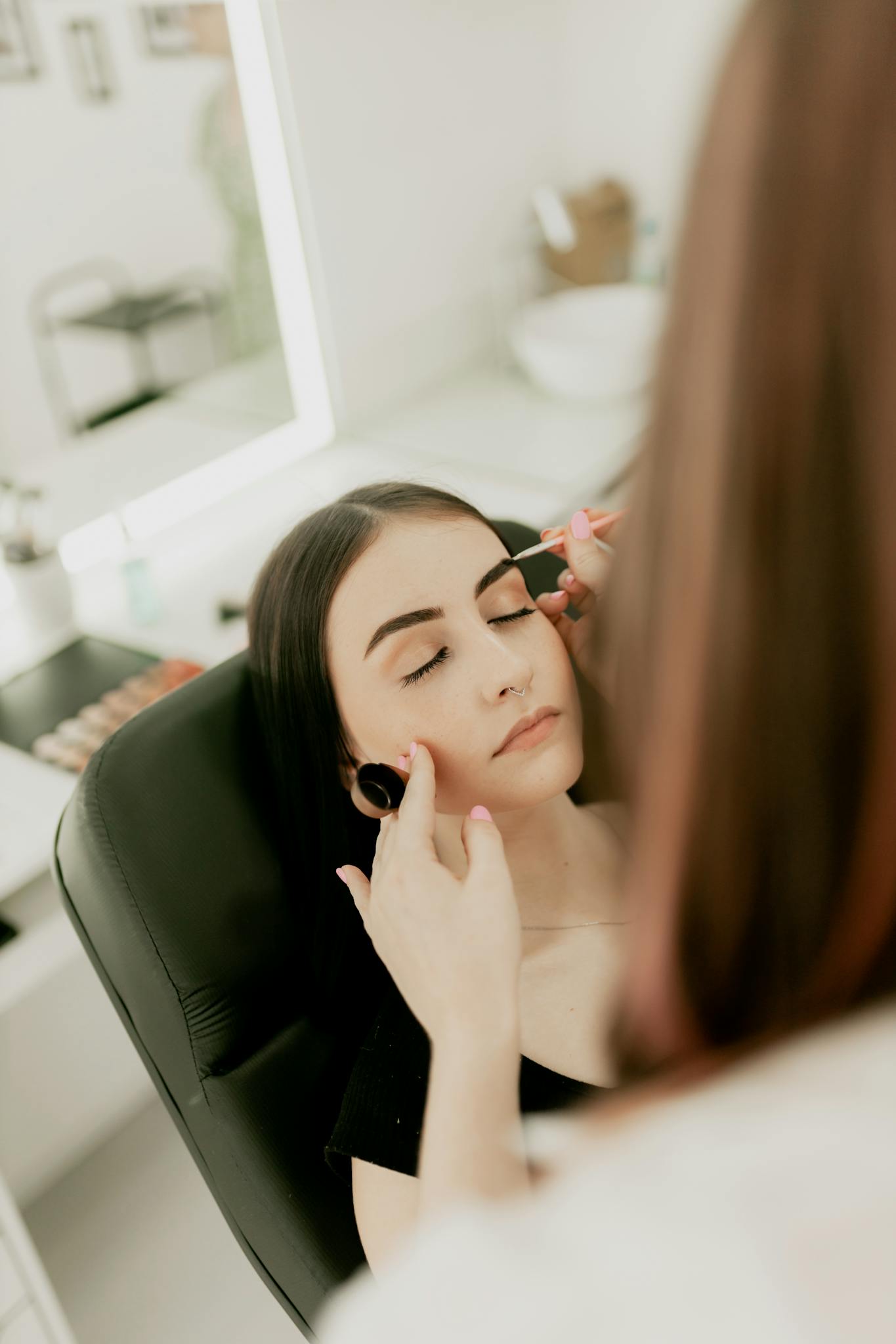 Makeup artist applying eyeliner to a woman in a beauty salon setting.